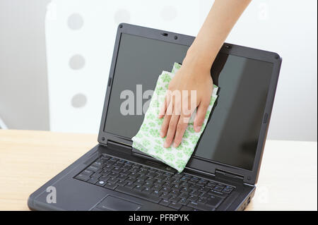 Woman polishing laptop screen on office desk using duster Stock Photo