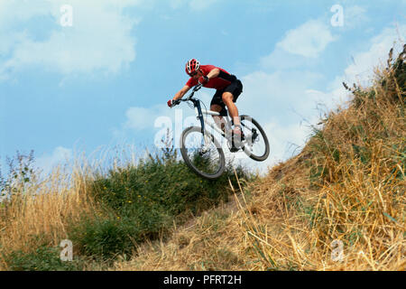 Man on mountain bike in mid-air jumping down steep hill Stock Photo