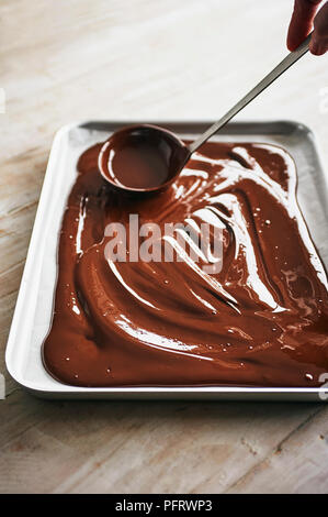 Making dark chocolate bark, spreading the melted chocolate on tray Stock Photo
