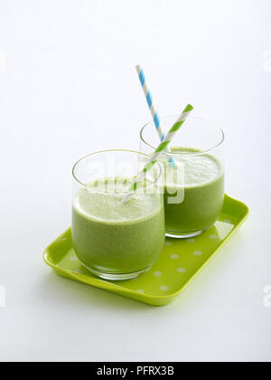 Two glasses filled with a green smoothies, served on a grey tray Stock Photo