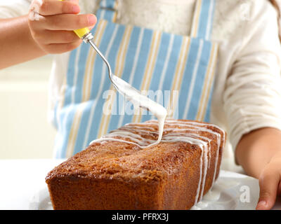 Lemon Drizzle Cake. Drizzling lemon icing on top of the cake (Step 6 of 6) Stock Photo