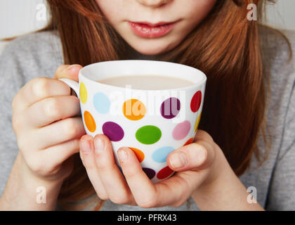 Child drinking a hot drink from a spotty mug Stock Photo