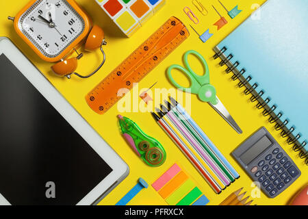 different school and office stationary and gadgets lying on a yellow background. free space for text Stock Photo
