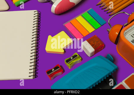 colored various school stationary lying on a purple surface. concept of office and educational supplies Stock Photo
