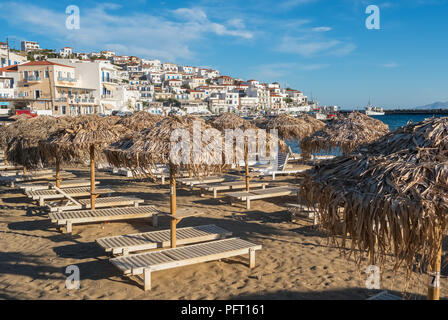 Umbrellas with sunbeds in picturesque Batsi village on  Andros island, Cyclades, Greece Stock Photo