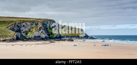 A Cornish beach scene at Mawgan Porth, Cornwall showing a steady line of keen surfers going for there early morning surfing session on the Atlantic. Stock Photo