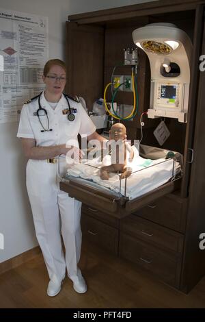 U.S. Navy Lt. Cmdr. Eileen Scott, department head of the Mother Infant Care Center at Robert M. Casey Naval Family Branch Clinic Iwakuni, demonstrates the capabilities of a neonatal resuscitation chamber at Marine Corps Air Station Iwakuni, Japan, May 30, 2018. The demonstration was part of the grand opening of the Robert M. Casey Naval Family Branch Clinic Iwakuni. The staff hosted the grand opening in order to display the facility’s new and improved capabilities. Stock Photo