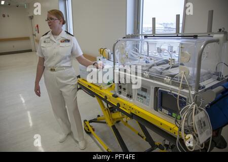 U.S. Navy Lt. Cmdr. Eileen Scott, department head of the Mother Infant Care Center at Robert M. Casey Naval Family Branch Clinic Iwakuni, demonstrates the capabilities of a neonatal transporter at Marine Corps Air Station Iwakuni, Japan, May 30, 2018. The demonstration was part of the grand opening of the Robert M. Casey Naval Family Branch Clinic Iwakuni. The staff hosted the grand opening in order to display the facility’s new and improved capabilities. Stock Photo