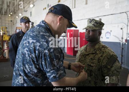 NORFOLK, Va. (May 24, 2018) -- Chief Aviation Ordnanceman Ra’Jard Roberts, from Longview, Texas, assigned to USS Gerald R. Ford’s (CVN 78) aviation intermediate maintenance department, receives a Navy and Marine Corps Achievement Medal from Cmdr. Steven Bryant, Ford’s maintenance officer, during an awards ceremony in the ship's hangar bay. Stock Photo