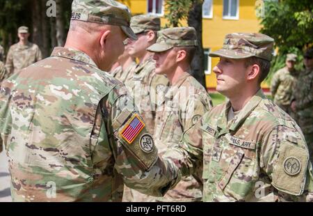 Yavoriv, Ukraine – Maj. Gen. Raymond Shields, commander of the New York Army National Guard, presents a challenge coin to Sgt. Alexander Rector at the Yavoriv Combat Training Center May 25. Rector, a Rushville, N.Y., native, serves as the Joint Multinational Training Group – Ukraine public affairs non-commissioned officer and was presented a coin in recognition of his hard work during the deployment. Stock Photo