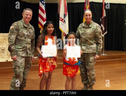 Col. Christopher Lindner, acting commander, William Beaumont Army Medical Center, and Command Sgt. Maj. Janell Ray, command sergeant major, WBAMC, present Khloe Andike and Angelma Anni, who performed a traditional Polynesian dance during the Fort Bliss Asian American Pacific Islander Heritage Month observance, a token of appreciation during the observance at the Centennial Banquet and Conference Center, Fort Bliss, May 23. Stock Photo