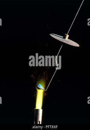 Flame experiment holding copper compound on platinum wire in Bunsen Burner flame, turning flame yellow Stock Photo