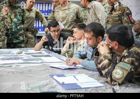 A translator, left, assigned to Train, Advise and Assist Command-South talks to Capt. Brandon Briscoe, center, operations and plans advisor for TAAC-South, May 25, 2018, at Camp Hero in Kandahar, Afghanistan. TAAC-South is a joint Army component command composed of Soldiers from the 40th Infantry Division, California National Guard and the 2nd Infantry Brigade Combat Team, 4th Infantry Division. Stock Photo