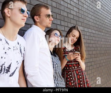 Group of Beautiful young people standing against  brick wall Stock Photo
