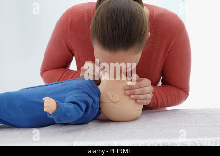 First aid medical checks and treatment of unconscious infant, using dummy, mouth to mouth, giving CPR Stock Photo
