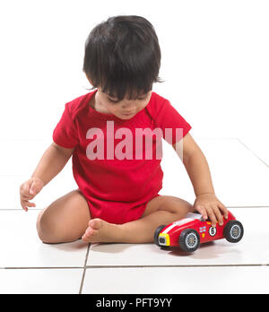 Baby boy (16 months) sitting playing with toy car Stock Photo
