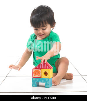 Baby boy (16 months) sitting playing with building blocks Stock Photo