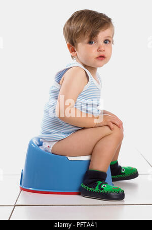 Boy sitting on a blue potty, 20 months Stock Photo