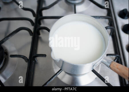 Warming milk in a saucepan on a stove Stock Photo