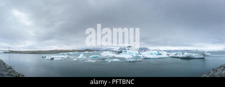 A large panoramic image of Jokulsarlon Glacial Lagoon with numerous icebergs visible floating in the lagoon. Stock Photo