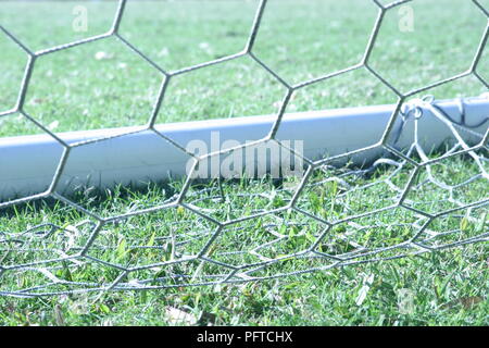 Detail of soccer goal with net resting on green grass of soccer pitch - landscape orientation Stock Photo
