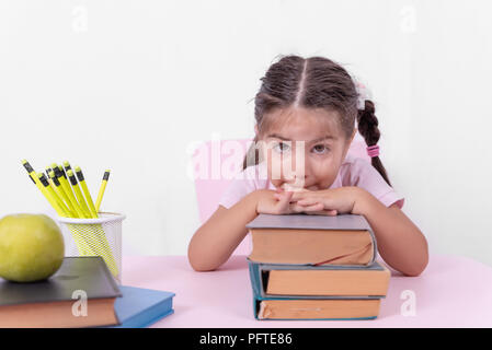 Cute little girl in school uniform looks thoughtful on books.Selective focus and copy space for editing Stock Photo