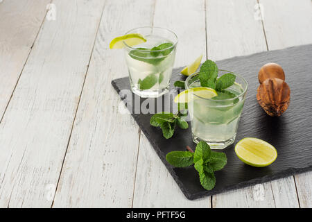 Summer drink. Citrus lemonade with mint and ice on white wooden background. Stock Photo