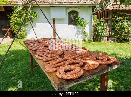 Bunch of Raw meat sausages on wooden table in the yard Stock Photo