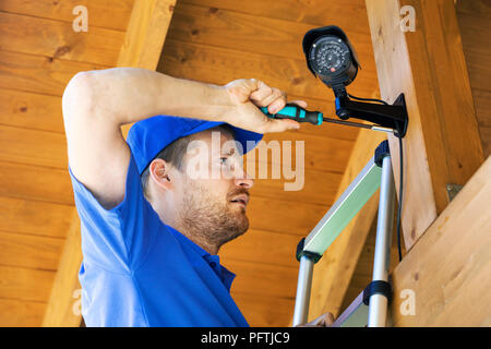 technician installing surveillance camera in the house carport Stock Photo