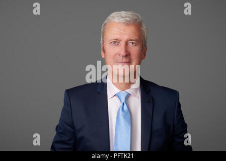 Close-up portrait of a senior professional man standing at isolated background and looking at camera. Stock Photo