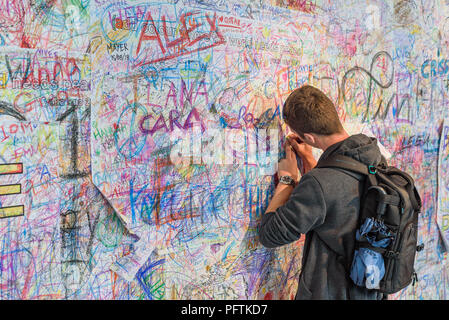 A young man writing on the Peace Wall  by Yoko Ono to 'Add colour where the world needs peace' at  the 'Double Fantasy' exhibition in Liverpool Stock Photo