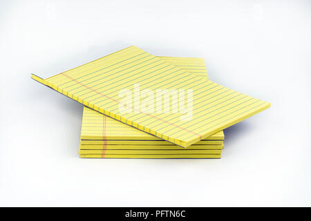 Yellow, ruled notepads neatly stacked with the top one offset that could be used for taking notes, or sharing ideas in school or office settings. Stock Photo