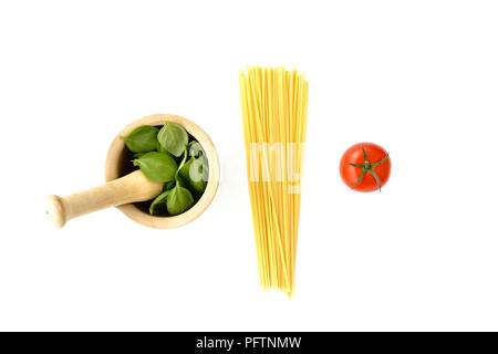 Mortar filled with fresh basil leaves, spaghetti and a tomato on white background. The colors of the Italian flag. Stock Photo