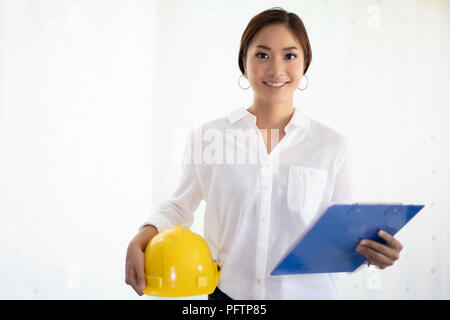 Asian women engineering inspecting and working and holding blueprints at office Stock Photo