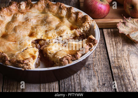 Apple pie with slice  and fresh apples on rustic wooden table