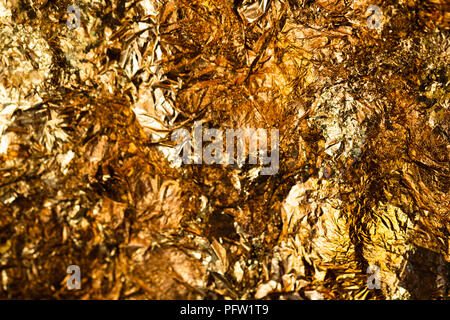 Shiny yellow gold leaf or scraps of gold foil background texture, surface from Back of Buddha image. Stock Photo