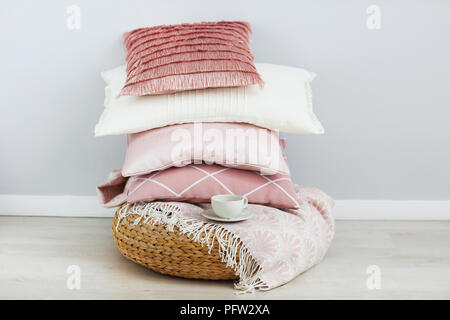 Pink and white pillows and cup of coffee on the wall background. Close up Stock Photo