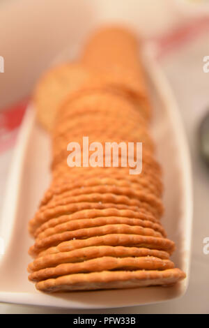 Crisp crackers biscuits on a long white dish with very shallow depth of field, out of focus background. Party buffet table set up Stock Photo