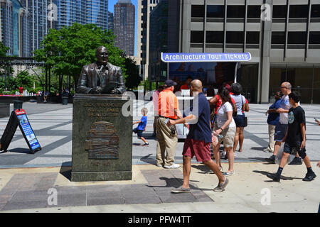 Tourists walk past the 2000 sculpture to Cubs announcer Jack Brickhouse outside the Tribune Tower in the Pioneer Court plaza on Michigan Avenue. Stock Photo