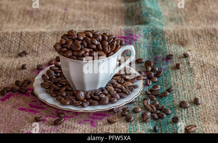A cup of coffee full of coffee beans on a tat Stock Photo