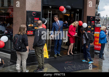 Staff with Angus Steakhouse show their menu to passers-by on Coventry Street, on 13th August 2018, in London, England. Angus Steakhouse is the original chain of steak restaurants based in central London's West End and has been serving both Londoners and visitors alike for 50 years. Stock Photo