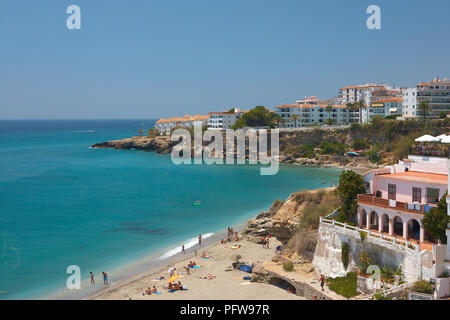 View of tourists on a Nerja golden beach, and deep blue sea water at a tourist hotspot in Andalusia southern Spain Stock Photo