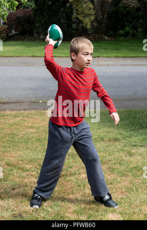 10 year old boy throwing a football on his lawn Stock Photo