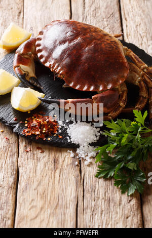 Country style: raw edible brown crab with ingredients for cooking close-up on a wooden table. vertical Stock Photo