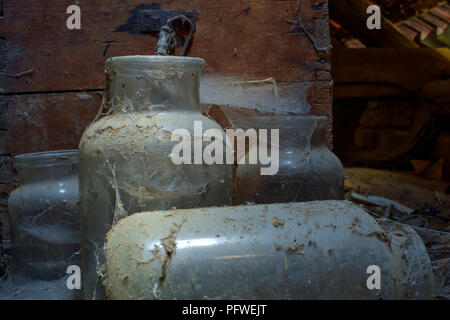 old glass jars and wooden box covered in dust and cobwebs laying undisturbed and forgotten in an old farmhouse attic zala county hungary
