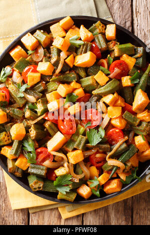Vegetable stew okra, sweet potatoes, tomatoes, onions and herbs closeup on a plate on the table. Vertical top view from above Stock Photo