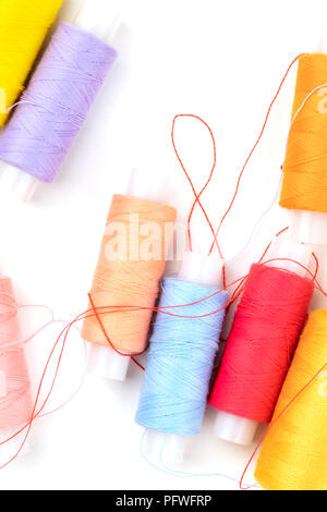 Overhead photo of thread spools of various colors on white with a place for text Stock Photo