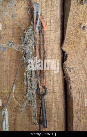 old key hanging by twine in an old dirty dusty shed Stock Photo