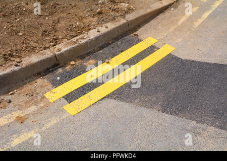 Tiny section of newly painted double yellow lines on road next to kerb Stock Photo