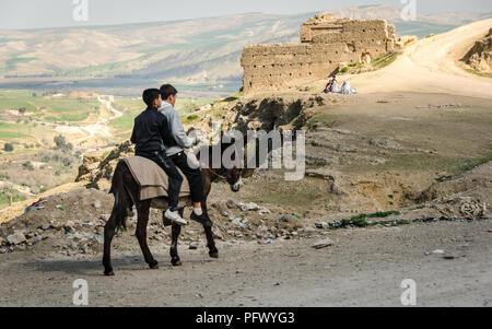 FEZ, MOROCCO - Februari 25, 2018: 2 boys riding a donkey on the sand roads in Morocco. Stock Photo